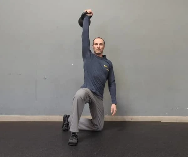 Coach Ryan demonstrates braced abs in the half-kneeling portion of the getup.
