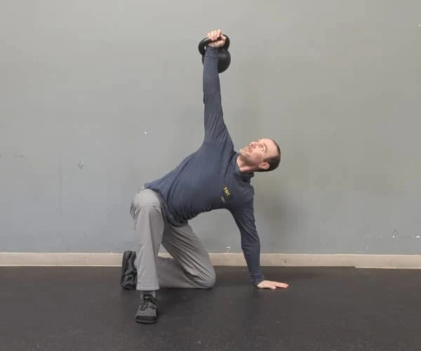 Coach Ryan demonstrates braced abs in the half-kneeling windmill portion of the getup.