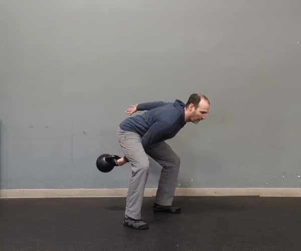 Coach Ryan demonstrates engaged abs in the bottom of the kettlebell swing.