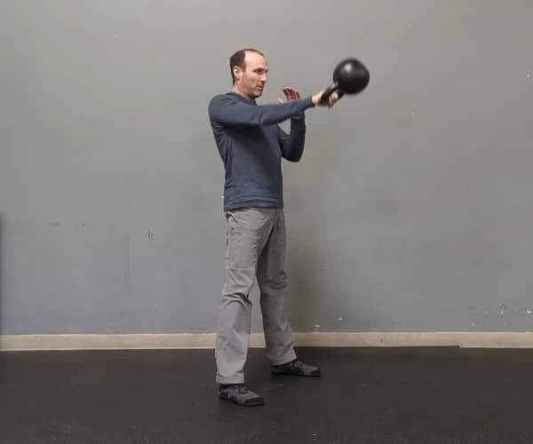 Coach Ryan demonstrates engaged abs in the top of the kettlebell swing.