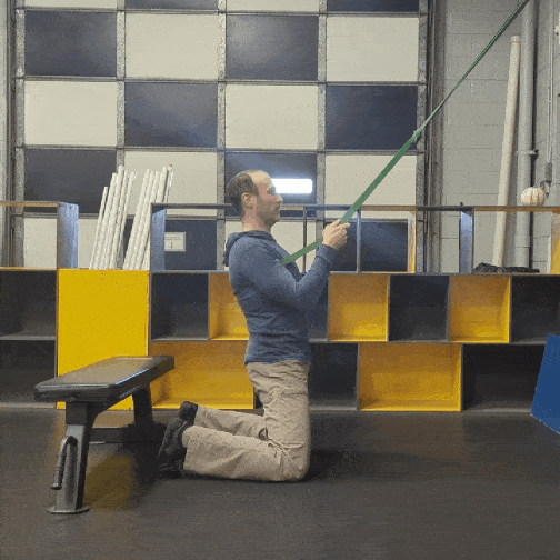 Coach Ryan demonstrates an assisted Reverse Nordic Curl using an exercise band.