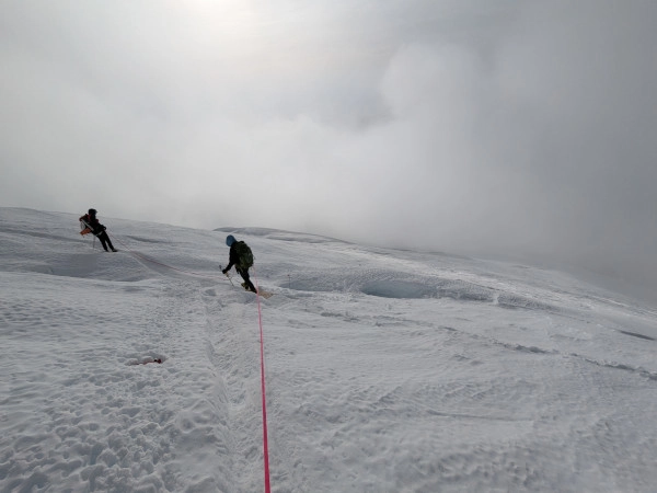 Coach Ryan's two climbing partners descend Mt. Rainier though the clouds.