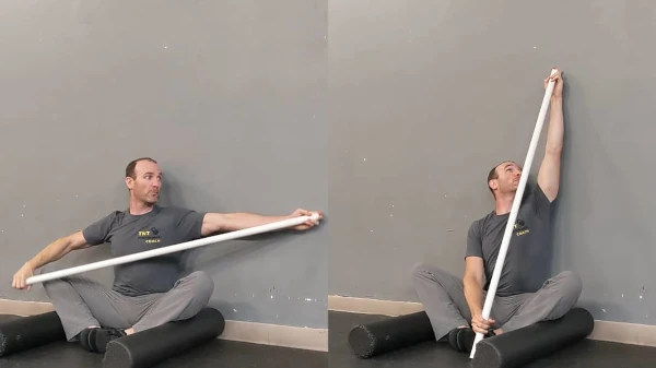 Coach Ryan demonstrates a one-arm stretch in the FMS Wall Sit.