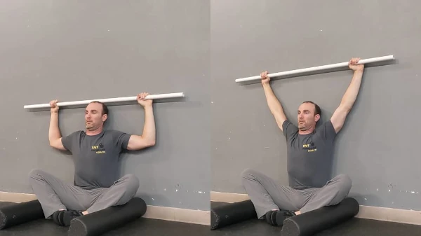 Coach Ryan demonstrates a two-arm stretch in the FMS Wall Sit.