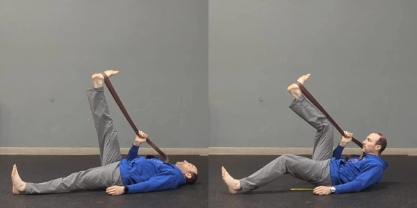 Coach Ryan demonstrates the correct way and an incorrect way to perform a belt-assisted hamstring stretch.