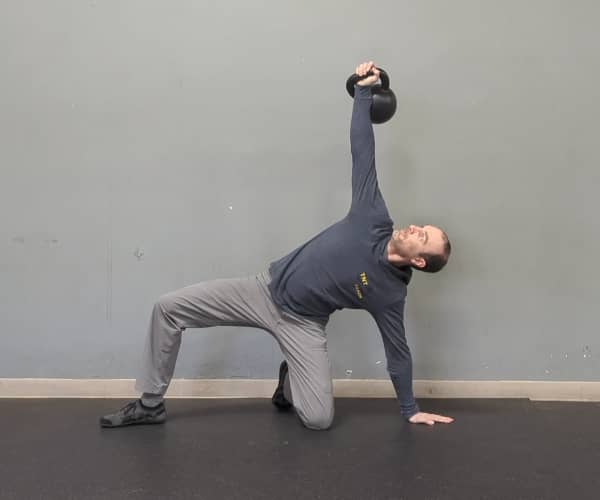 Coach Ryan demonstrates a not-so-good position of the hand and legs in the half-kneeling portion of the getup—the hand is in a line with the foot and knee instead of at a right angle.