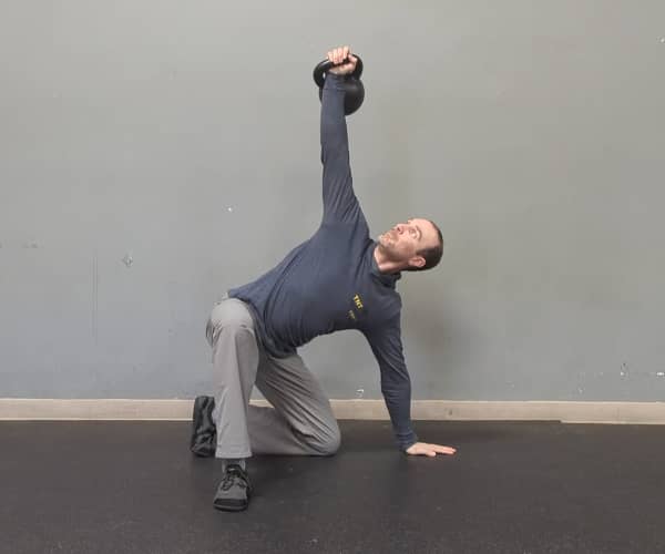 Coach Ryan demonstrates a good, triangular-shaped position of the hand and legs in the half-kneeling portion of the getup.