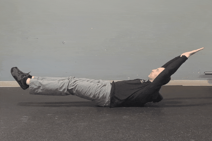 Coach Ryan demonstrates what NOT to do during a hollow rocker—flexing the hips and sitting up.