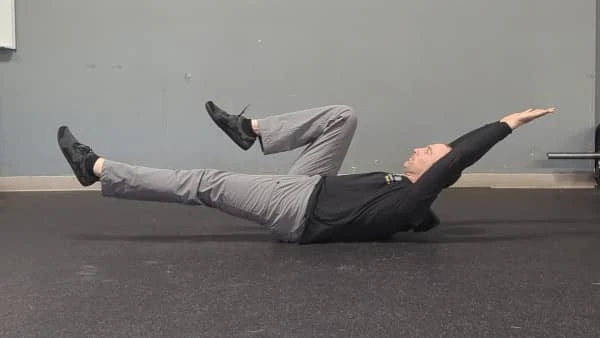 Coach Ryan demonstrates a one-leg-bent, one-leg-straight hollow hold.