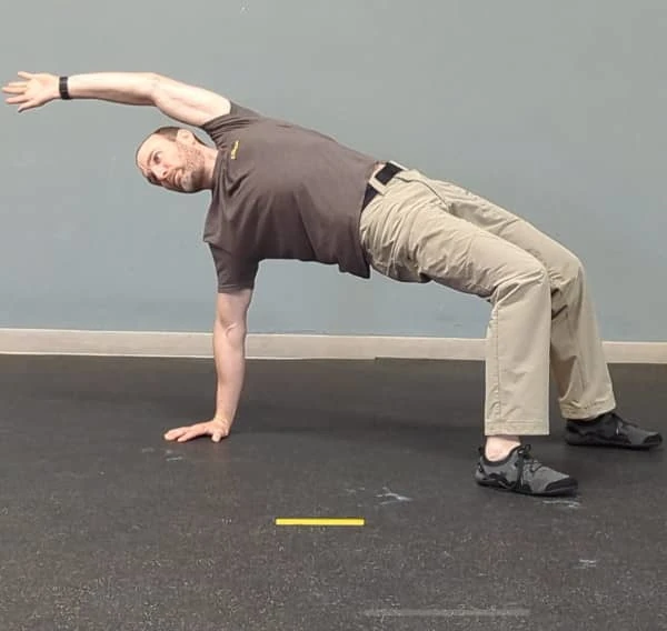 Coach Ryan demonstrates a common T-spine Bridge mistake—reaching over the head instead of across the body.