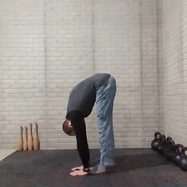Coach Ryan demonstrates a standing straight-leg hamstring stretch—and touches his palms to the floor.