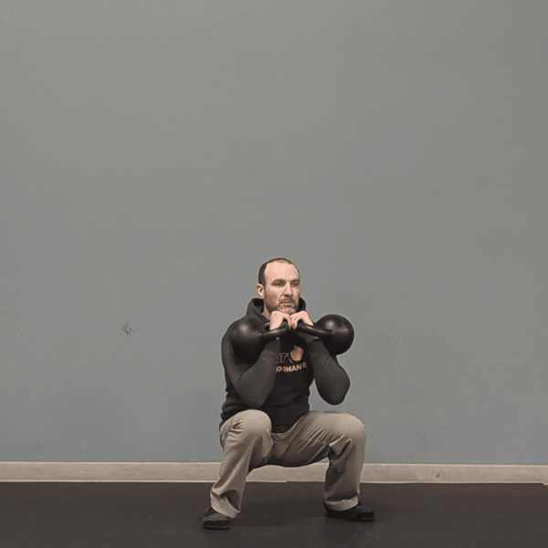 Coach Ryan demonstrates valgus collapse at the bottom of a double kettlebell front squat.